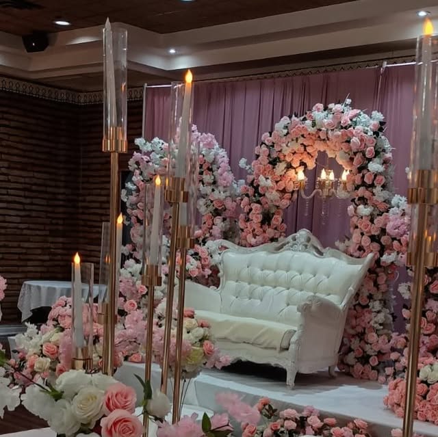 Floral arch mandap with a white sofa stage and full pink and ivory blooms